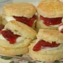 Exquisita mesa de té y scons rellenos con crema y frutillas