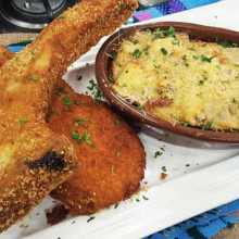 Milanesas de costillas de cerdo con hueso con gratén de papas al roquefort y tomates asados